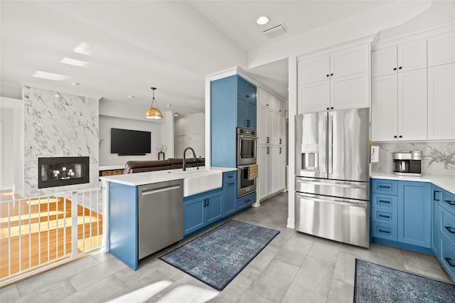 kitchen featuring sink, decorative light fixtures, blue cabinetry, white cabinetry, and stainless steel appliances