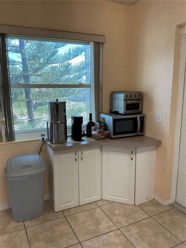 kitchen featuring light tile patterned flooring and white cabinets