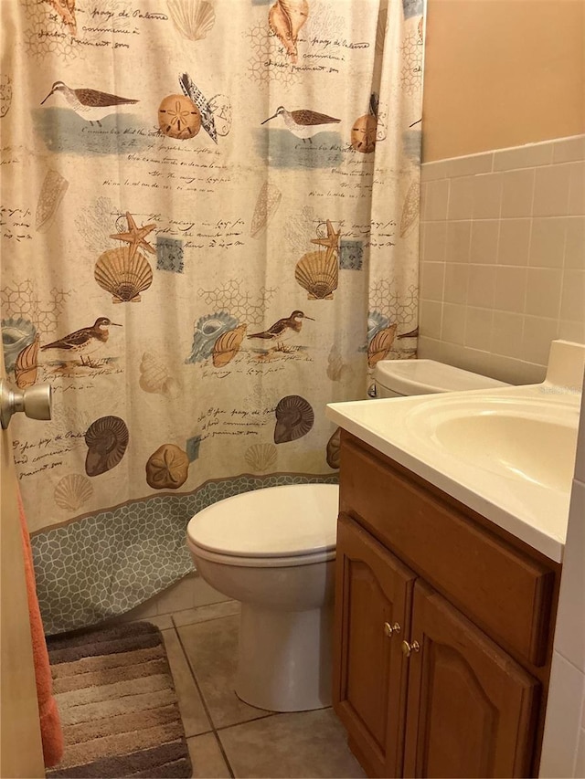 bathroom featuring toilet, tile walls, vanity, curtained shower, and tile patterned flooring