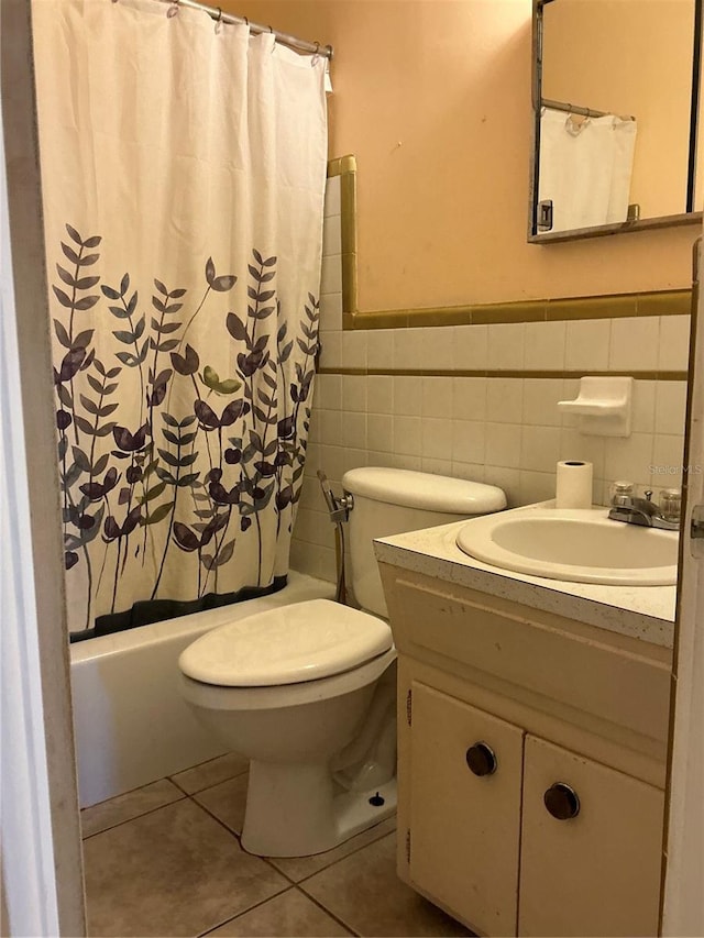 full bathroom with tile walls, shower / bath combination with curtain, tile patterned flooring, vanity, and toilet