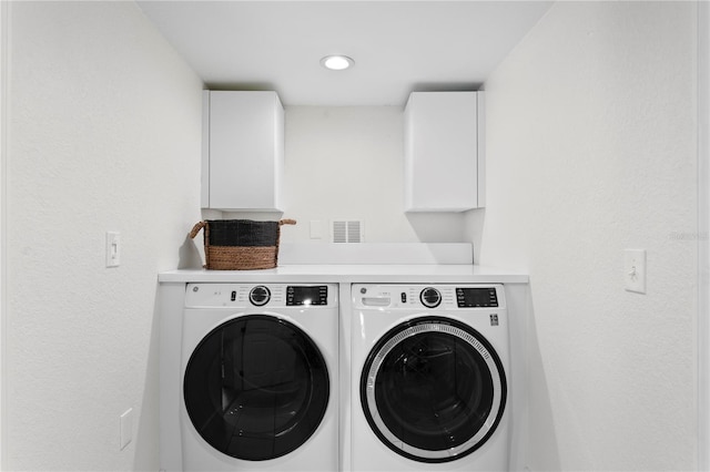 clothes washing area featuring cabinets and washing machine and dryer