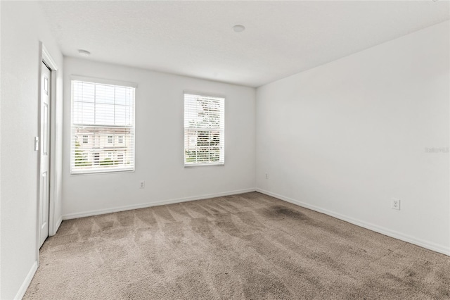 unfurnished room with light colored carpet and plenty of natural light