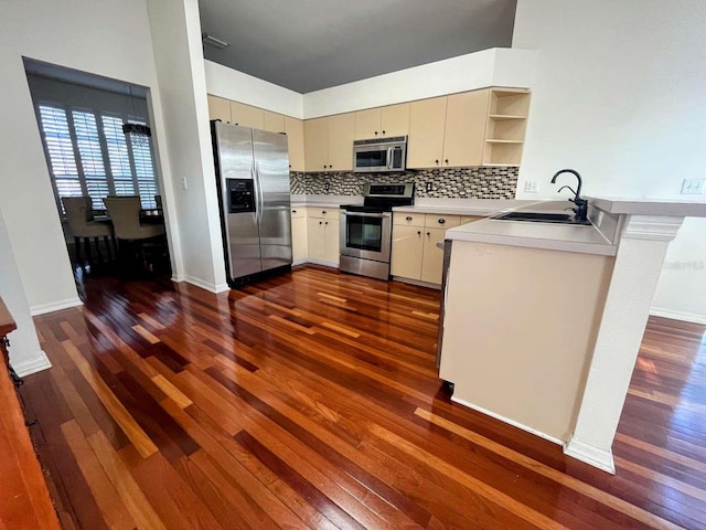 kitchen featuring sink, appliances with stainless steel finishes, dark hardwood / wood-style flooring, cream cabinets, and backsplash