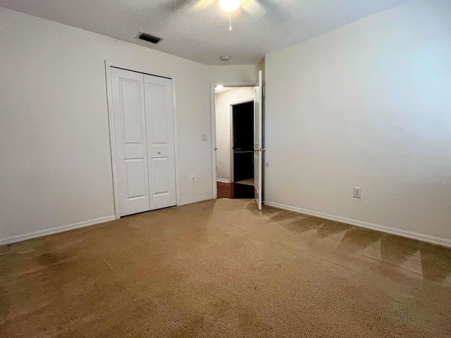 unfurnished bedroom featuring a textured ceiling, a closet, ceiling fan, and carpet flooring