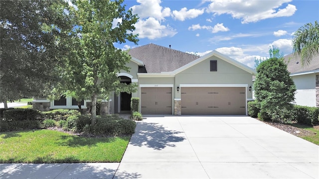 view of front of house featuring stone siding, an attached garage, driveway, and stucco siding