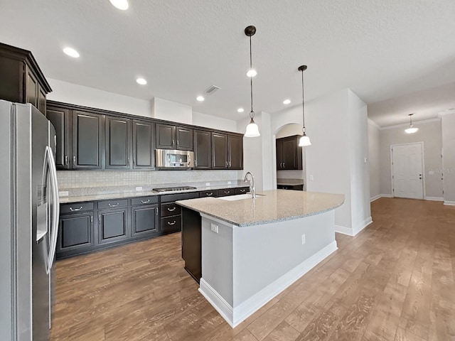 kitchen with backsplash, sink, an island with sink, decorative light fixtures, and stainless steel appliances