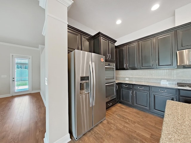 kitchen featuring crown molding, light hardwood / wood-style flooring, appliances with stainless steel finishes, tasteful backsplash, and light stone counters