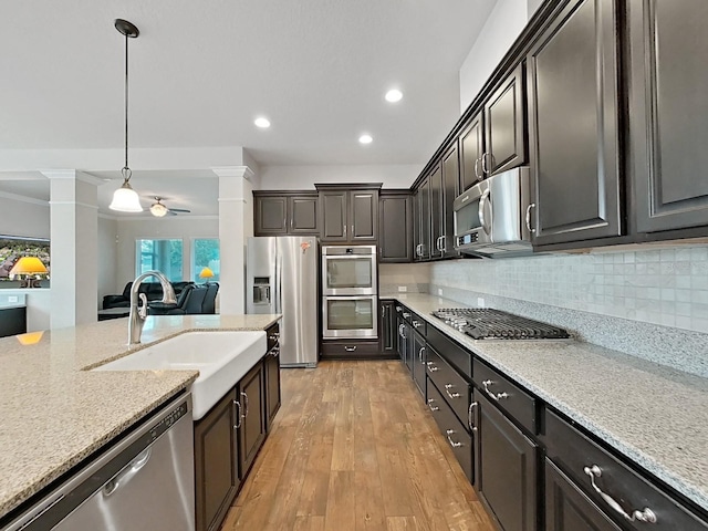 kitchen featuring ceiling fan, sink, stainless steel appliances, decorative columns, and pendant lighting