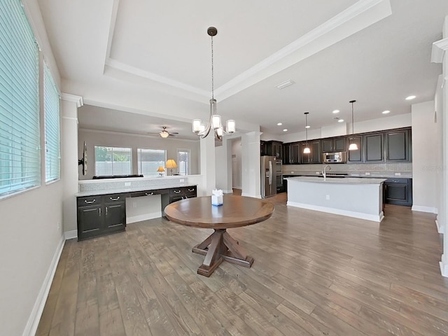 kitchen with hanging light fixtures, ceiling fan, appliances with stainless steel finishes, tasteful backsplash, and a tray ceiling