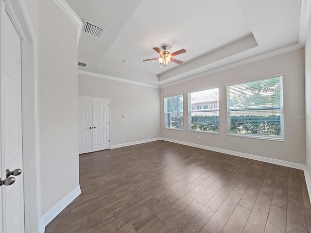 unfurnished room featuring a raised ceiling, ceiling fan, and dark wood-type flooring