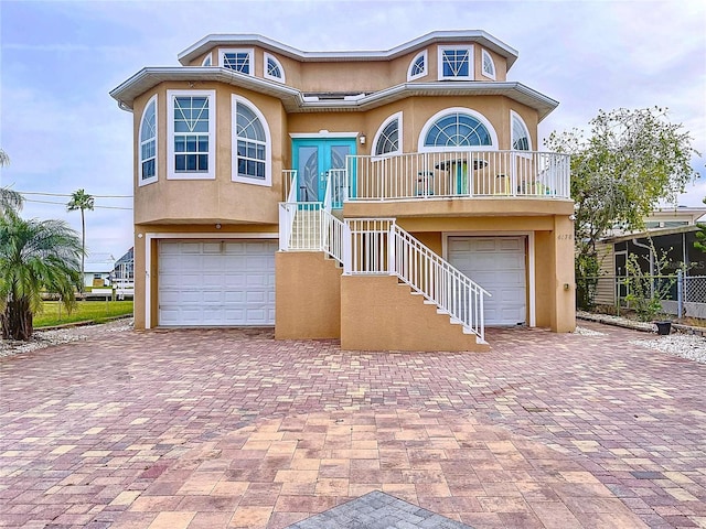 view of front of house featuring a garage, decorative driveway, stairs, and stucco siding