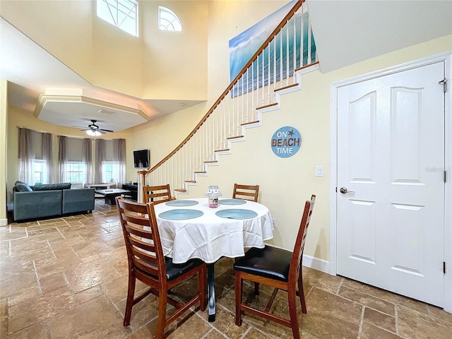 dining space with a towering ceiling and ceiling fan