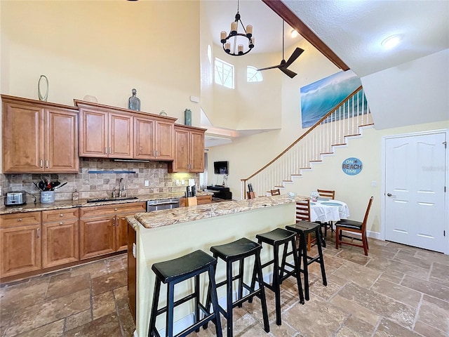 kitchen with sink, a breakfast bar, a center island, a high ceiling, and decorative backsplash