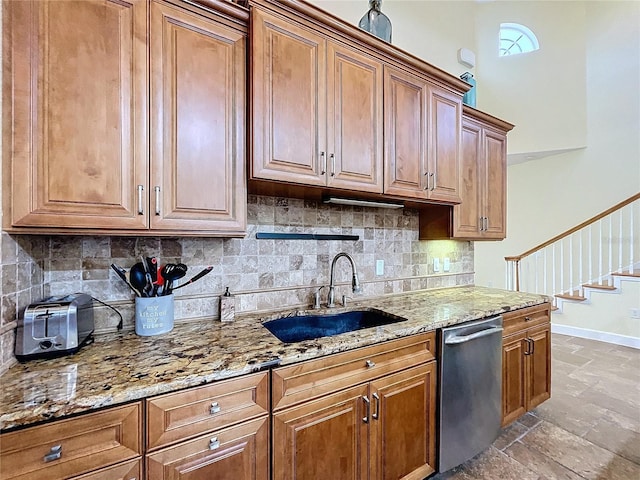 kitchen featuring tasteful backsplash, stainless steel dishwasher, light stone countertops, and sink