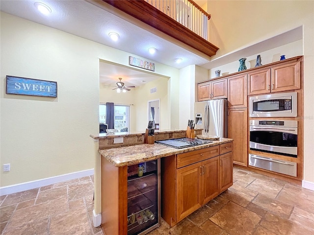 kitchen with wine cooler, ceiling fan, stainless steel appliances, and light stone countertops