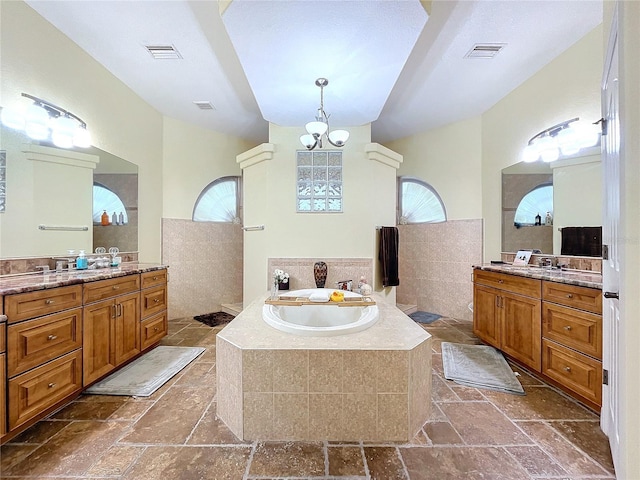 bathroom with vanity, a wealth of natural light, and tiled bath