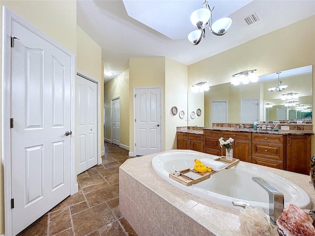 bathroom featuring an inviting chandelier, vanity, and a relaxing tiled tub