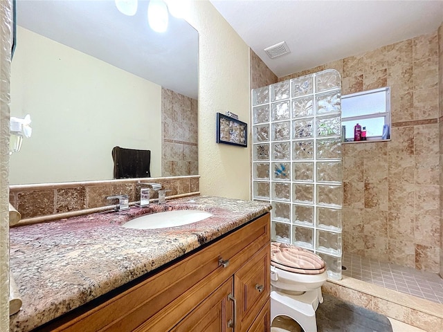 bathroom with vanity, tile patterned flooring, toilet, and a tile shower