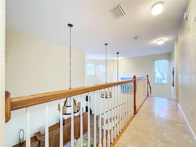 hall with light tile patterned flooring and a healthy amount of sunlight