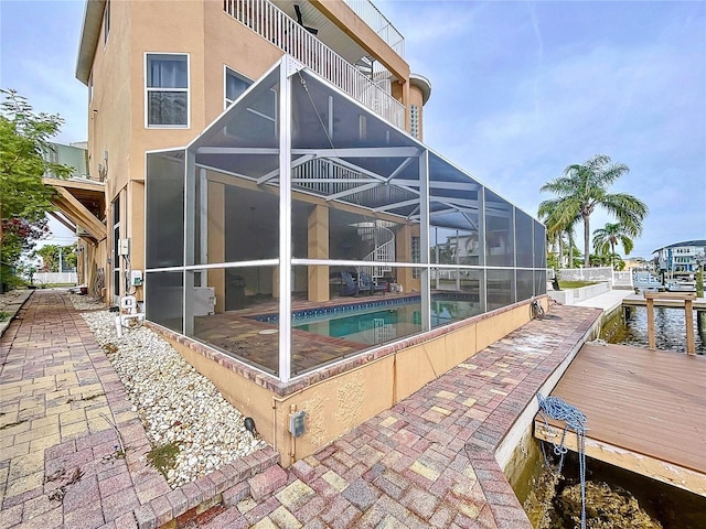 back of house featuring a water view, a patio, a lanai, and a balcony