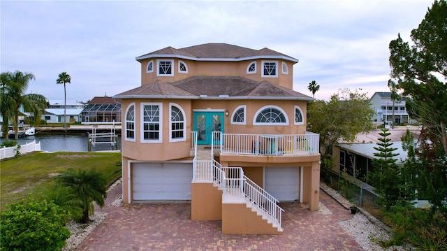 view of front of house with a garage, decorative driveway, a water view, and stucco siding