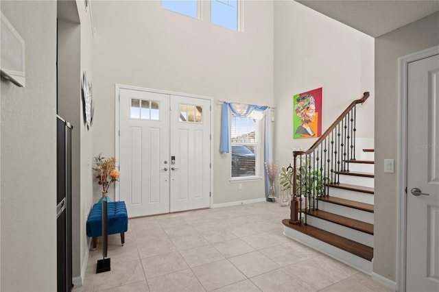 foyer featuring a healthy amount of sunlight, light tile patterned flooring, and a high ceiling