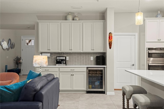 kitchen featuring white cabinets, decorative light fixtures, stainless steel double oven, and beverage cooler