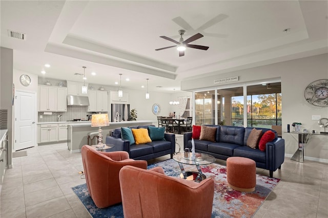 tiled living room featuring a raised ceiling and ceiling fan