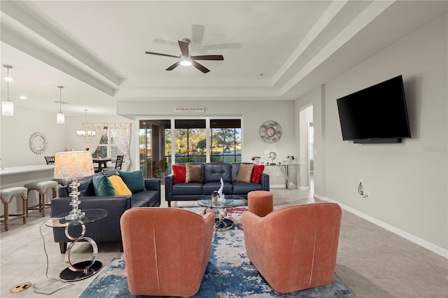 tiled living room with a tray ceiling and ceiling fan