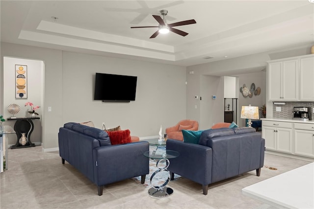 living room with light tile patterned floors, a tray ceiling, and ceiling fan