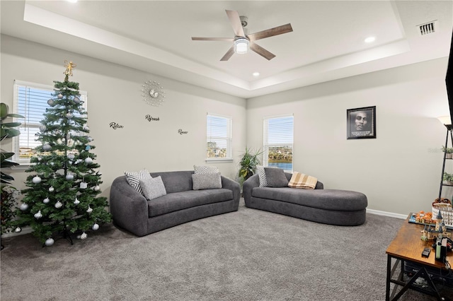 carpeted living room with a raised ceiling and ceiling fan