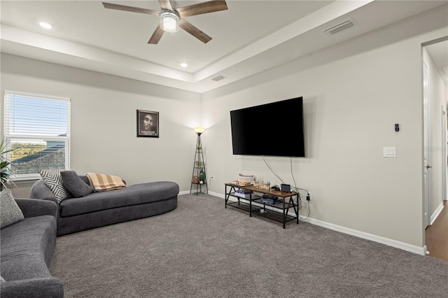 living room with carpet flooring, ceiling fan, and a tray ceiling