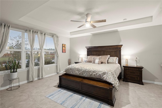 bedroom featuring light tile patterned floors, a tray ceiling, and ceiling fan