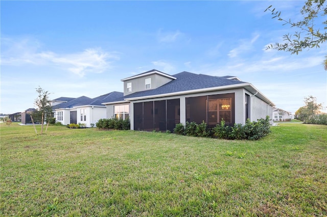 rear view of house with a yard and a sunroom