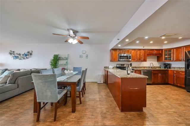 kitchen featuring sink, light stone counters, ceiling fan, kitchen peninsula, and appliances with stainless steel finishes