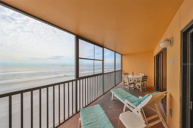 sunroom featuring a beach view and a water view