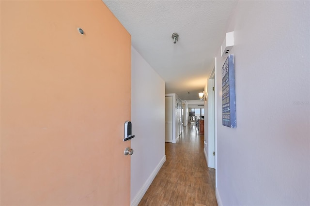 hall featuring wood-type flooring and a textured ceiling