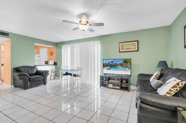 tiled living room featuring ceiling fan and a textured ceiling