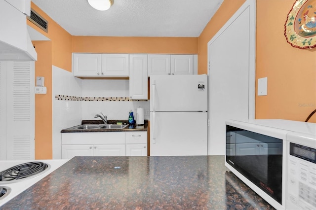 kitchen featuring white refrigerator, sink, a textured ceiling, tasteful backsplash, and white cabinetry