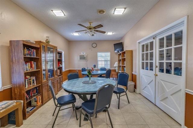 tiled dining area with a textured ceiling, an AC wall unit, and ceiling fan