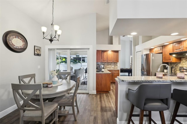 dining room with a notable chandelier, sink, high vaulted ceiling, and dark hardwood / wood-style floors