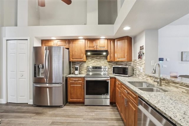 kitchen with sink, stainless steel appliances, light stone countertops, and ceiling fan