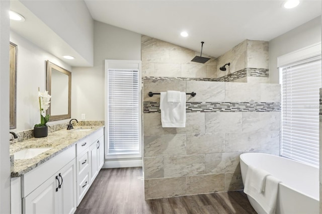 bathroom with shower with separate bathtub, vaulted ceiling, wood-type flooring, and vanity