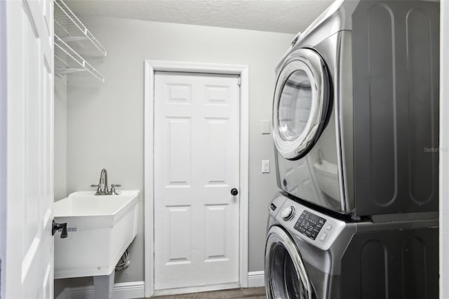 laundry room with stacked washer and clothes dryer, sink, and a textured ceiling