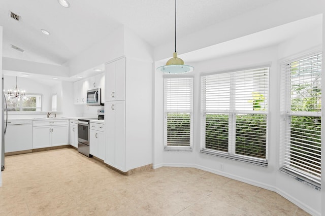 kitchen with lofted ceiling, white cabinets, appliances with stainless steel finishes, and pendant lighting