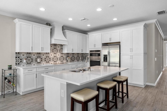 kitchen with white cabinets, appliances with stainless steel finishes, custom range hood, and sink