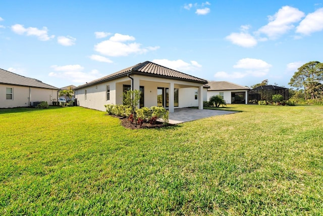 back of house with glass enclosure, a patio, and a lawn