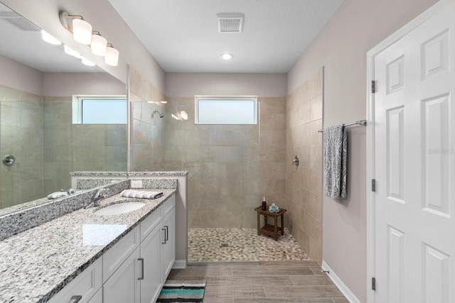 bathroom with vanity and tiled shower