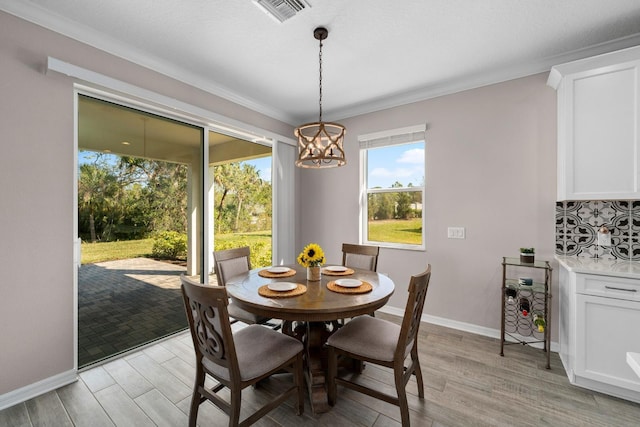 dining space featuring a notable chandelier, light hardwood / wood-style flooring, and ornamental molding