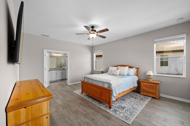 bedroom with ensuite bath, light hardwood / wood-style flooring, and ceiling fan